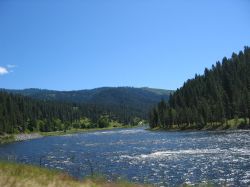 A rolling river parallels the road while motorcycling in Idaho.