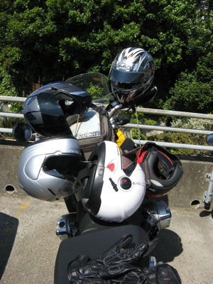 Too many helmets locked together on one motorcycle.